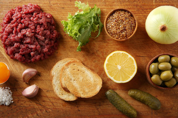 Beef tartare ingredients on wooden cutting board
