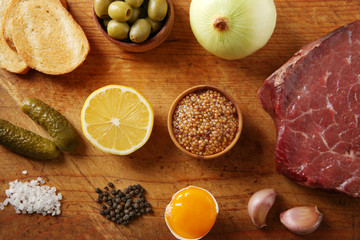 Beef tartare ingredients on wooden cutting board