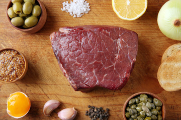 Beef tartare ingredients on wooden cutting board