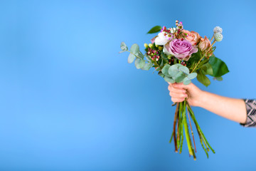 Female hand holding a bouquet of roses on blue background