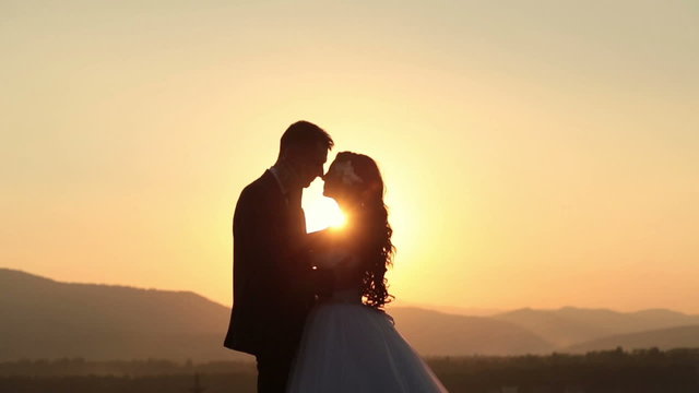 Beautiful wedding couple kiss on the sunset in the mountains