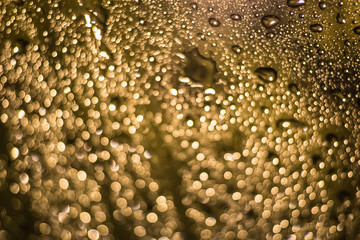 Abstract blurred dark yellow light from water drop at the windscreen bokeh background