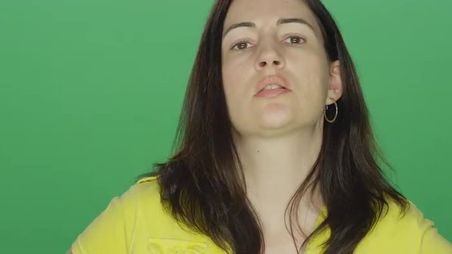 Young brunette woman looking really upset, on a green screen studio background