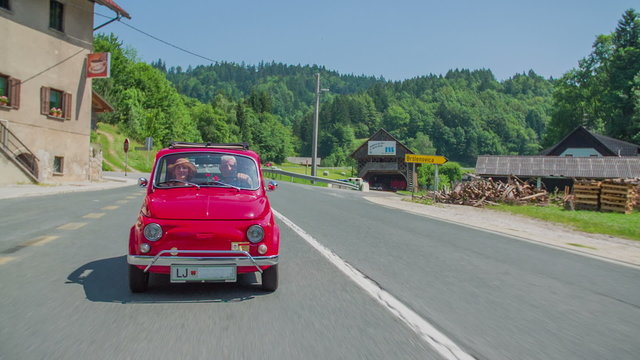 Red vintage zastava driving through a small town
