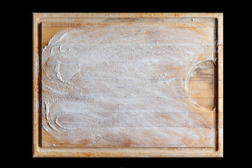 Rough wooden rectangular used cutting board background with flour directly from above on black background