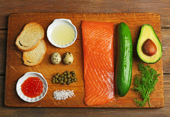 Tasty ingredients of salmon tartare on cutting board, flat lay