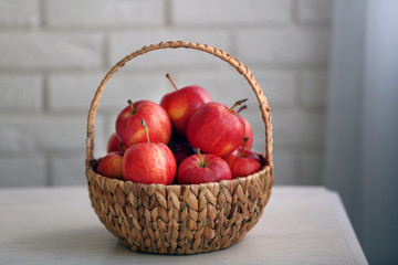 Ripe red apples in basket on kitchen table