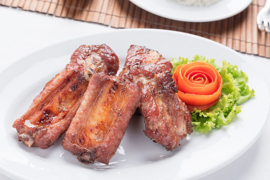 fried pork spare ribs on the white dish with a rose make from tomato on the side