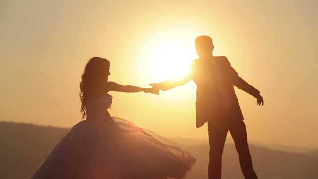 Beautiful wedding couple dances on sunset close up