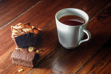 Chocolate brownies and cup of tea on wooden table