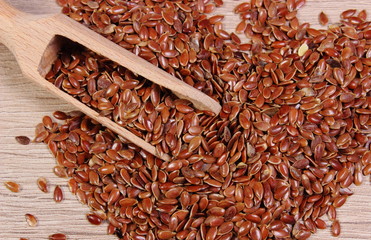 Heap of linseed with spoon on wooden background