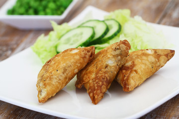 Indian samosas with green side salad on white plate, closeup
