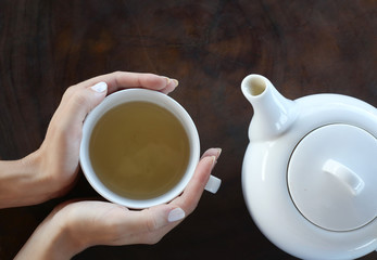 Tea time. Girl holding a cup of tea on the table