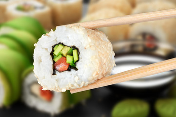 Sushi rolls with avocado, salmon and sesame seeds.
