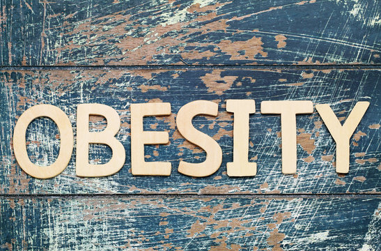 Word obesity written with wooden letters on rustic surface
