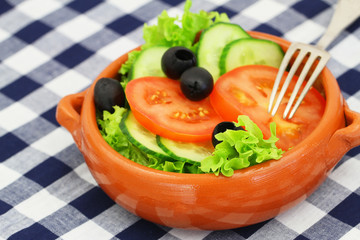 Bowl of salad with lettuce, tomatoes, cucumber and black olives

