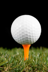 golf ball on a tee on black background