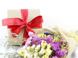 craft paper gift box with ribbon bow and flower bouquet with fabric texture