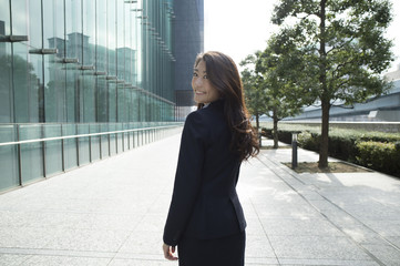 Woman wearing a business suit is turned around with a smile