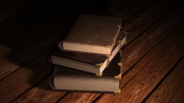 Old leather books on wooden table in candlelight