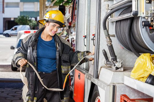 Smiling Firefighter Adjusting Water Hose In Truck