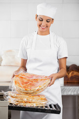 Female Baker Stacking Packed Pizza Breads