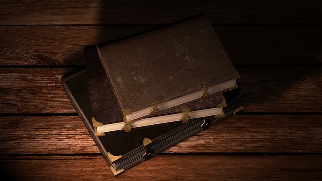 Old leather books on wooden table in candlelight