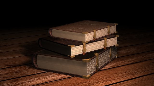 Old leather books on wooden table in candlelight