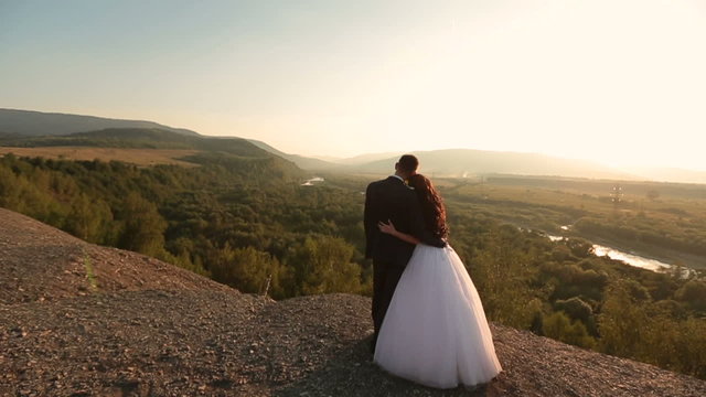 Gorgeous wedding couple on the top of the mountain on back view