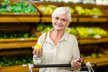 Senior woman holding phone and an apple