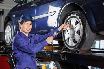 Mechanic Filling Air Into Car Tire At Garage