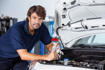 Fototapeta na wymiar Confident Mechanic Leaning On Car With Open Hood