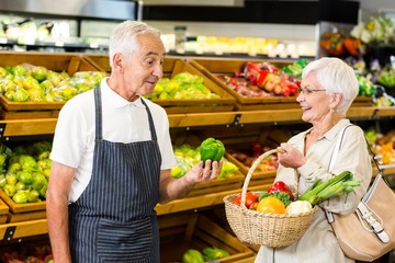 Senior customer and worker discussing vegetables