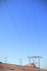 High voltage towers standing by a road on rocky desert, USA