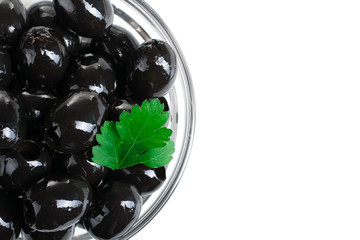 a bunch of delicious and healthy olives pitted with green leaf in glass bowl on white isolated background