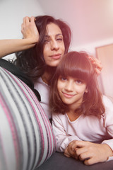 Young mother and daughter sitting on the sofa