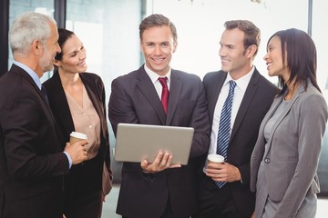 Businesspeople standing together with a laptop