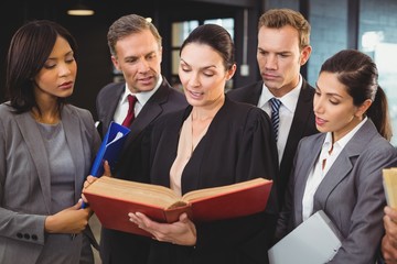 Lawyer reading a law book and interacting with businesspeople