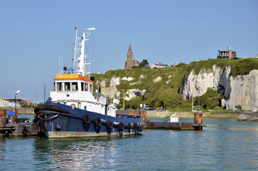 Fishing boat in the port of dieppe and the church Notre Dame in the background on the cliffs. Dieppe is a commune in the Seine-Maritime department in the Haute-Normandie France - obrazy, fototapety, plakaty