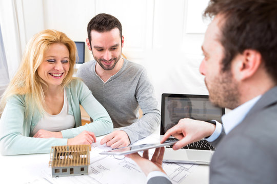 Real estate agent present project on tablet to a young couple