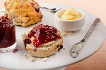scone with strawberry jam and butter on a cake stand