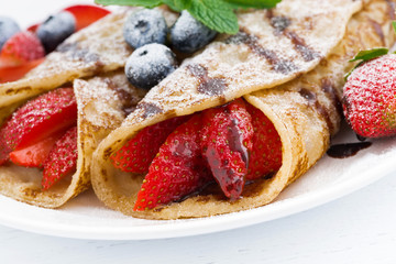 crepes with fresh berries and chocolate sauce on plate, closeup