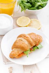 croissant with salted salmon and fresh arugula, top view