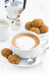 cup of cappuccino and macaroons on white wooden table