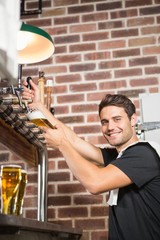 Handsome barman pouring a pint of beer