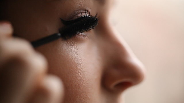young female paints eyelashes mascara