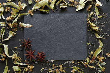 Tea, herbs and anise on slate background with copy space.