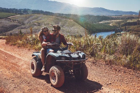 Happy couple riding on a quad bike