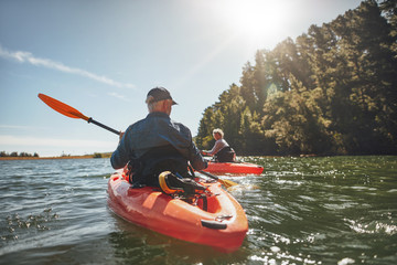 Couple kayaking in the lake on a sunny day - obrazy, fototapety, plakaty