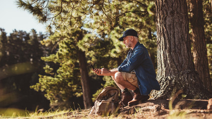 Senior man on hike in nature using a compass